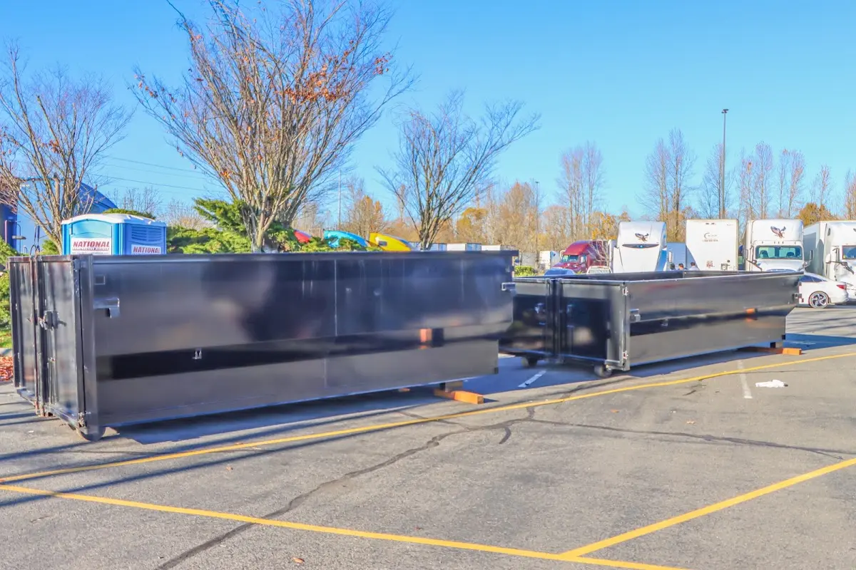 Professional dumpster rental service with roll-off container on residential driveway in Aston